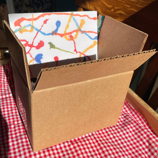 Open cardboard box with colorful paper on a red and white checkered tablecloth