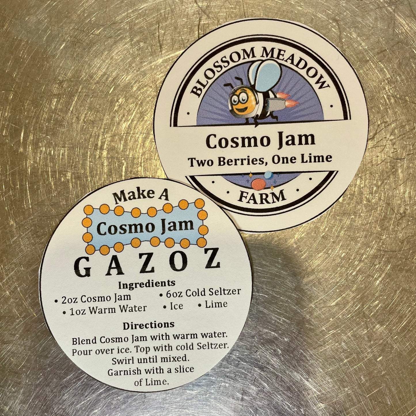 Two round labels for Cosmo Jam on a metallic surface